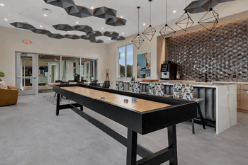 Clubhouse game room with shuffleboard and bar seating